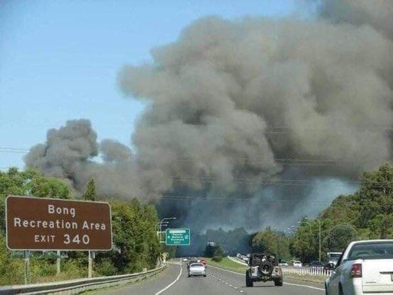 Highway scene with brown road sign reading Bong Recreation Area, Exit 340. Massive smoke billows in the air in the background