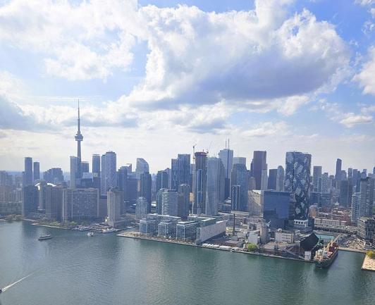 Looking out plane window at city of Toronto skyline with large clouds above it