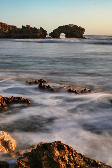 Bridgewater Bay, nestled in Blairgowrie on Victoria’s Mornington Peninsula, is a rugged coastal gem renowned for its dramatic sandstone cliffs, expansive rock pools, and the iconic "Jumping Rock"—a natural diving platform that attracts thrill-seekers. Accessible via a steep staircase from St Johns Wood Road, the bay forms a natural amphitheater surrounded by high calcarenite bluffs, with a sandy section between the rock formations. The area is popular with families for its extensive rock pools, which are great to explore at low tide. However, the beach is not patrolled and is considered dangerous for swimming due to the exposed rocks, reefs, and surf. Visitors are advised to keep an eye on the tides and waves, and wear sensible footwear as some of the rocks are covered in slippery seaweed. The bay is also accessible as part of the Coastal Walk.