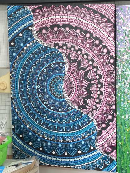 a  mandala  design, cropped  at the  sides, a wavy white line of dots running diagonally, half he mandala is blue, half pink