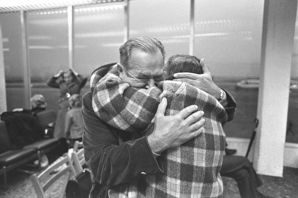 responses to adversity: black and white photograph of two elderly men hugging in an airport lounge