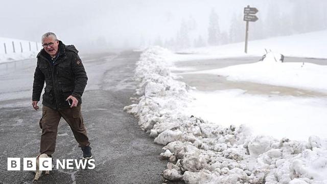 A man walks along snow-covered fields after heavy snowfall at the Aravis Pass