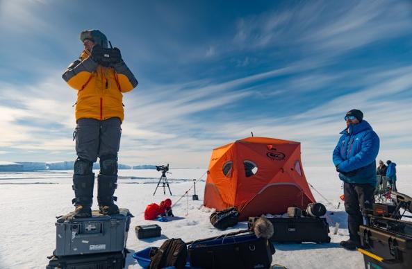 Bertie Gregory standing on a box with a drone remote in hishand, with Callum Stronach as a spotter. (credit: National Geographic/Ben Joiner)