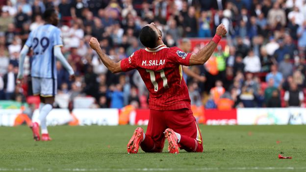 Mohamed Salah sinks to his knees and raises his hands in the air as he celebrates Liverpool FC's Premier League title win. | Credit: Getty Images