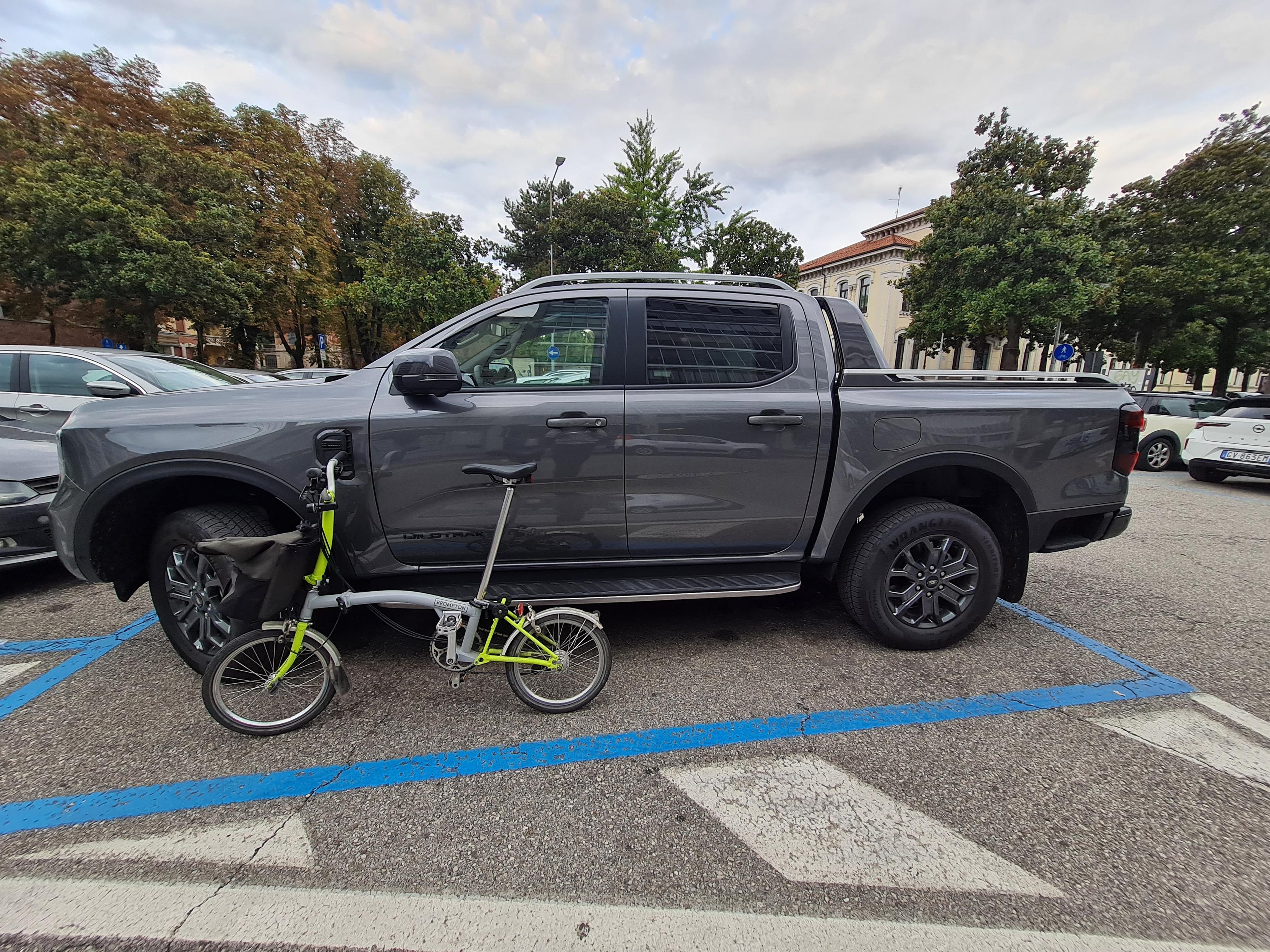 Bicicletta Brompton messa a lato di un pickup americano per confronto.