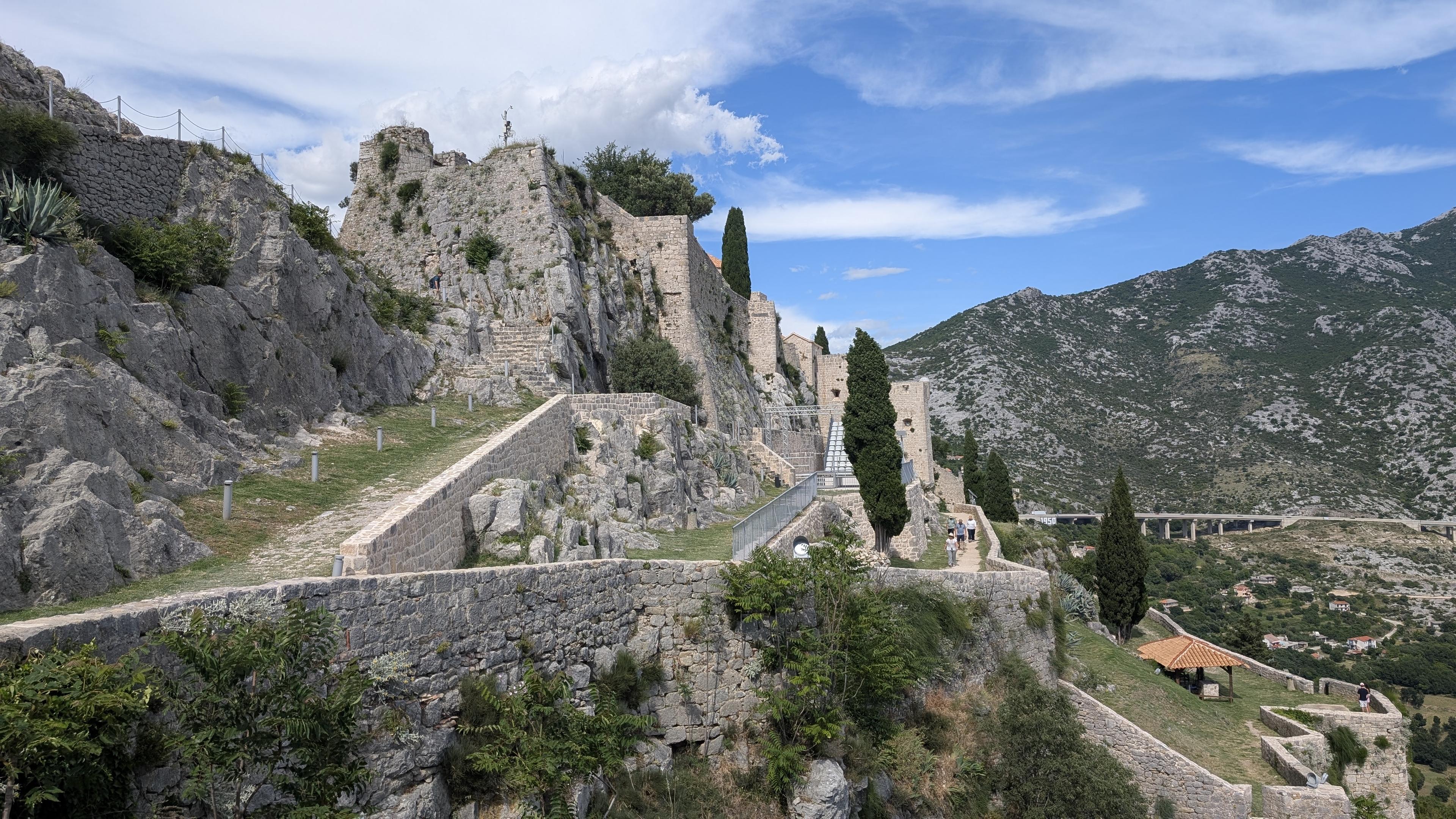 Una parte del castello di Klis, con le mura, una porta d'ingresso e un'autostrada sullo sfondo