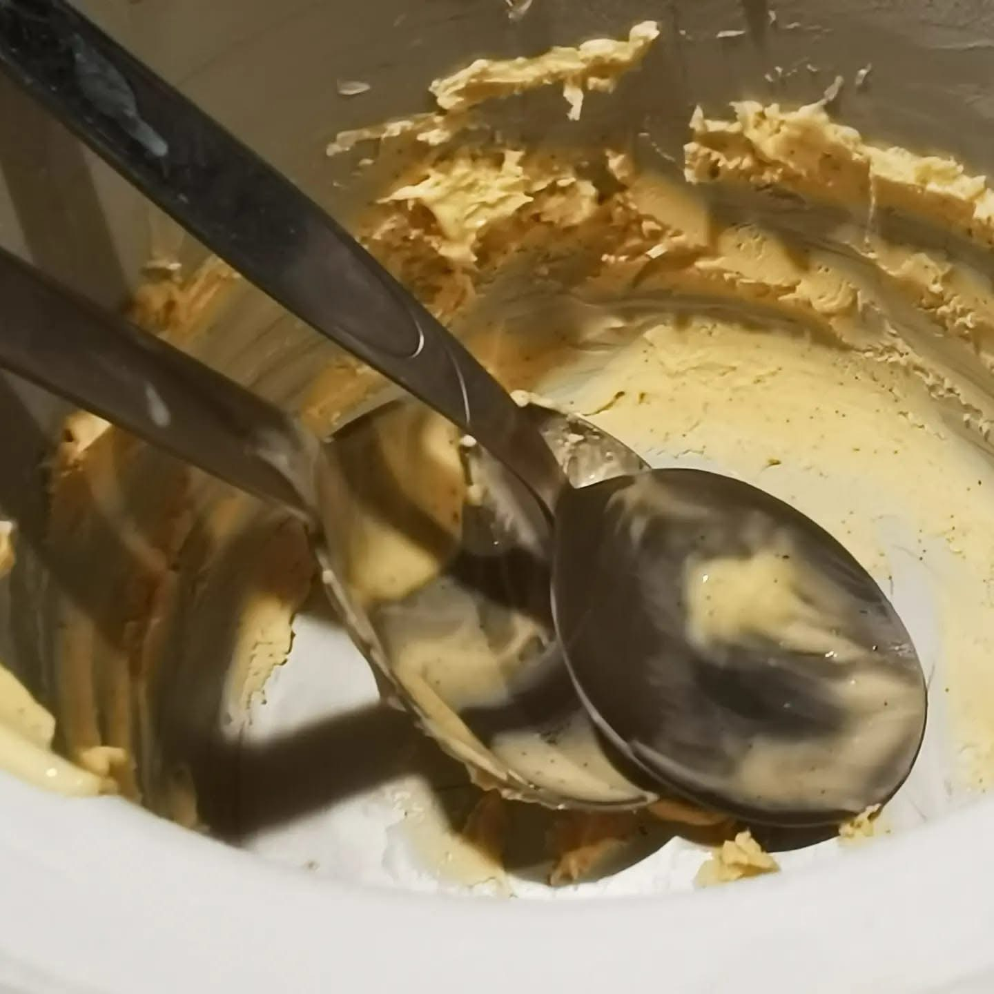 Cucchiai nella gelatiera con gelato ai bordi di essa