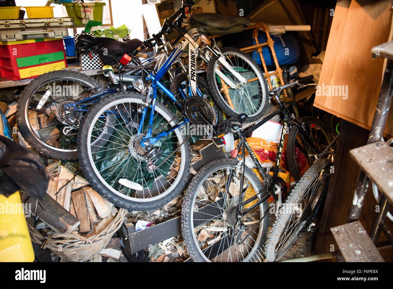 Foto stock di quattro o più biciclette sopra una catasta di ciarpame in un garage.