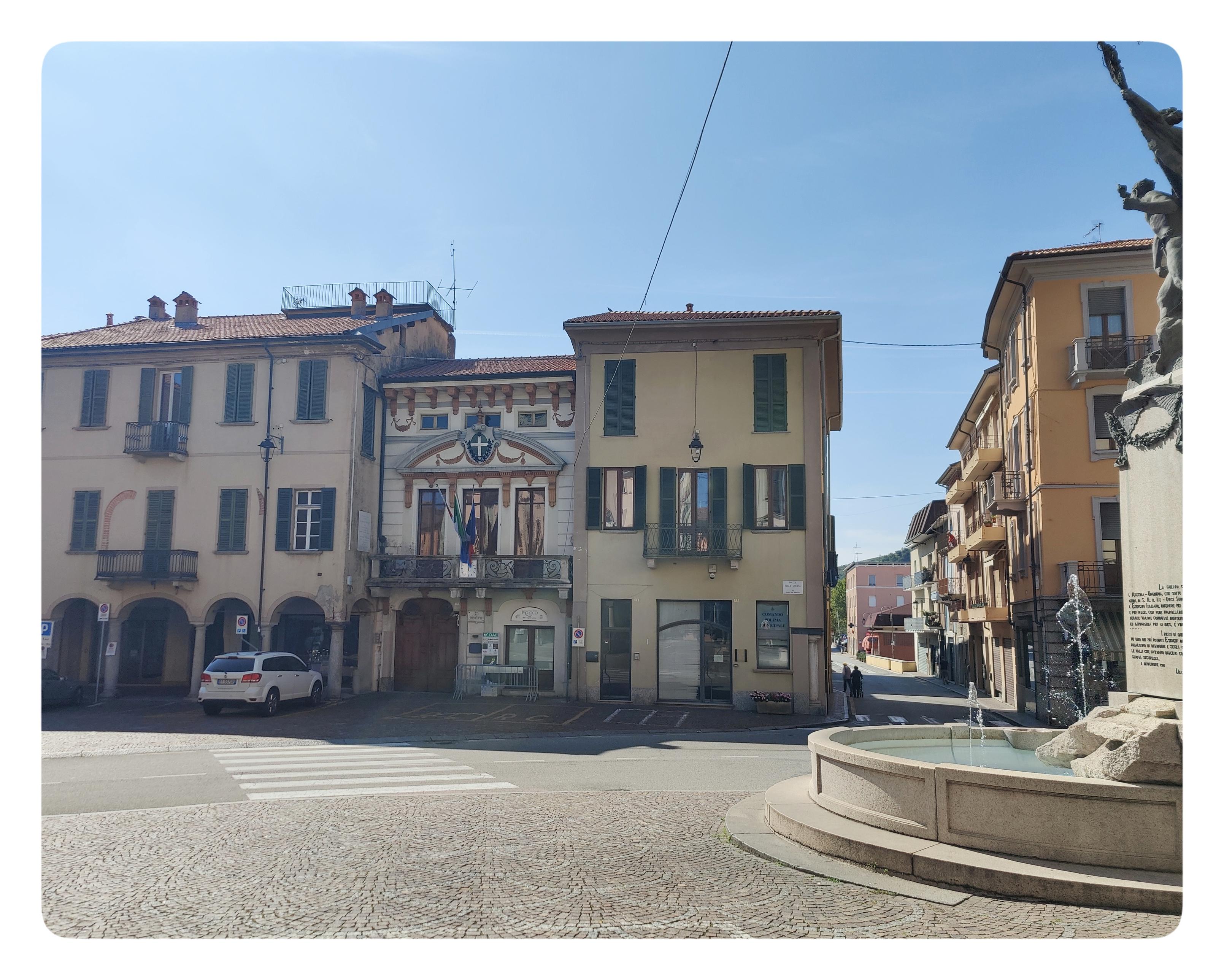 Il Palazzo Comunale di Romagnano Sesia. Piazza Libertà. Nella piazza si trova una fontana (a destra nella foto). Tra i palazzi che vi si affacciano, si riconosce il Palazzo Comunale. La facciata è riccamente decorata.