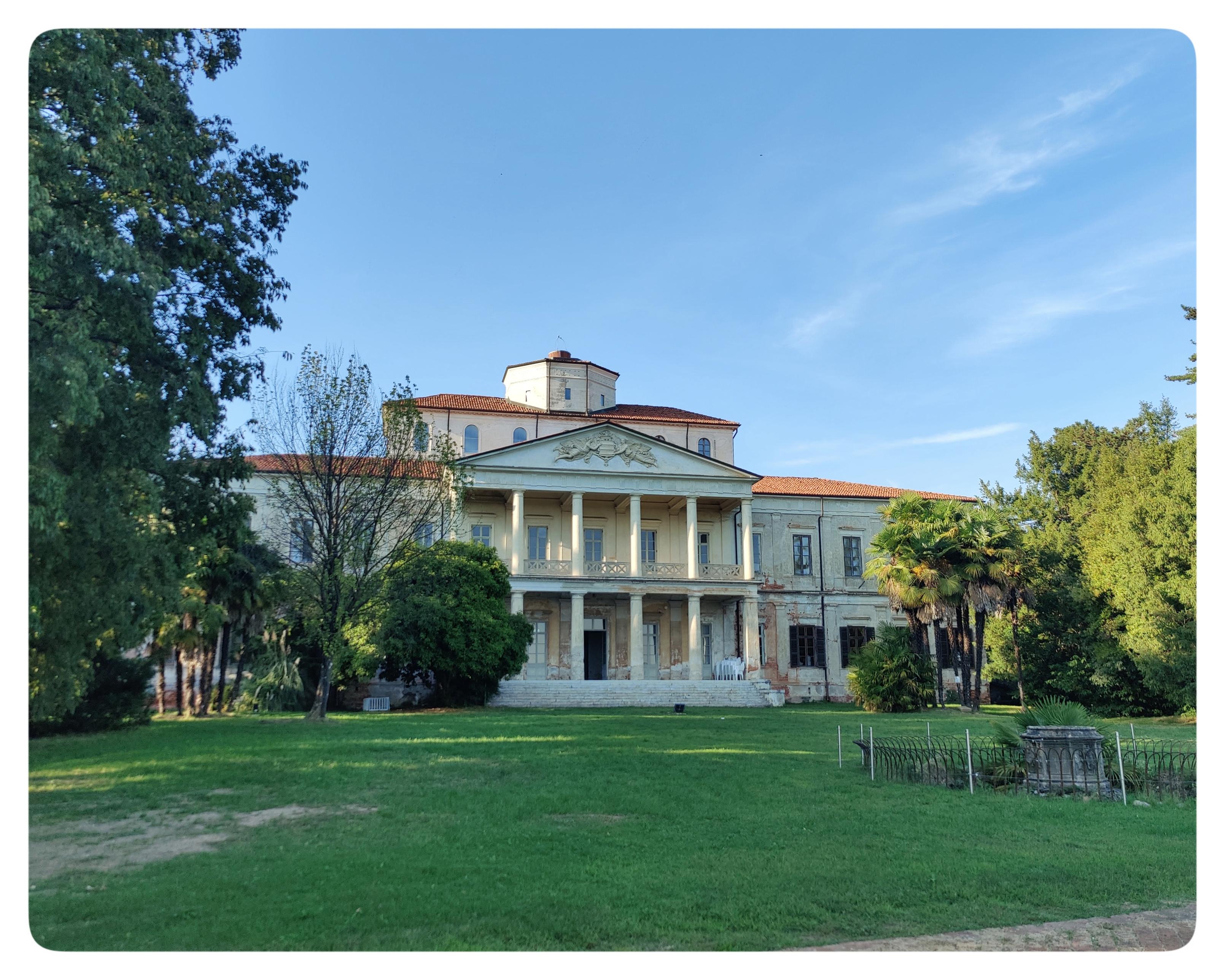 La facciata di Villa Caccia e il suo giardino. Lo stile è quello tipico dell'Antonelli. Il giardino seguiva lo stile italiano. Oggi è tenuto come prato all'inglese. Il giardino è circondato dagli alti alberi del parco.