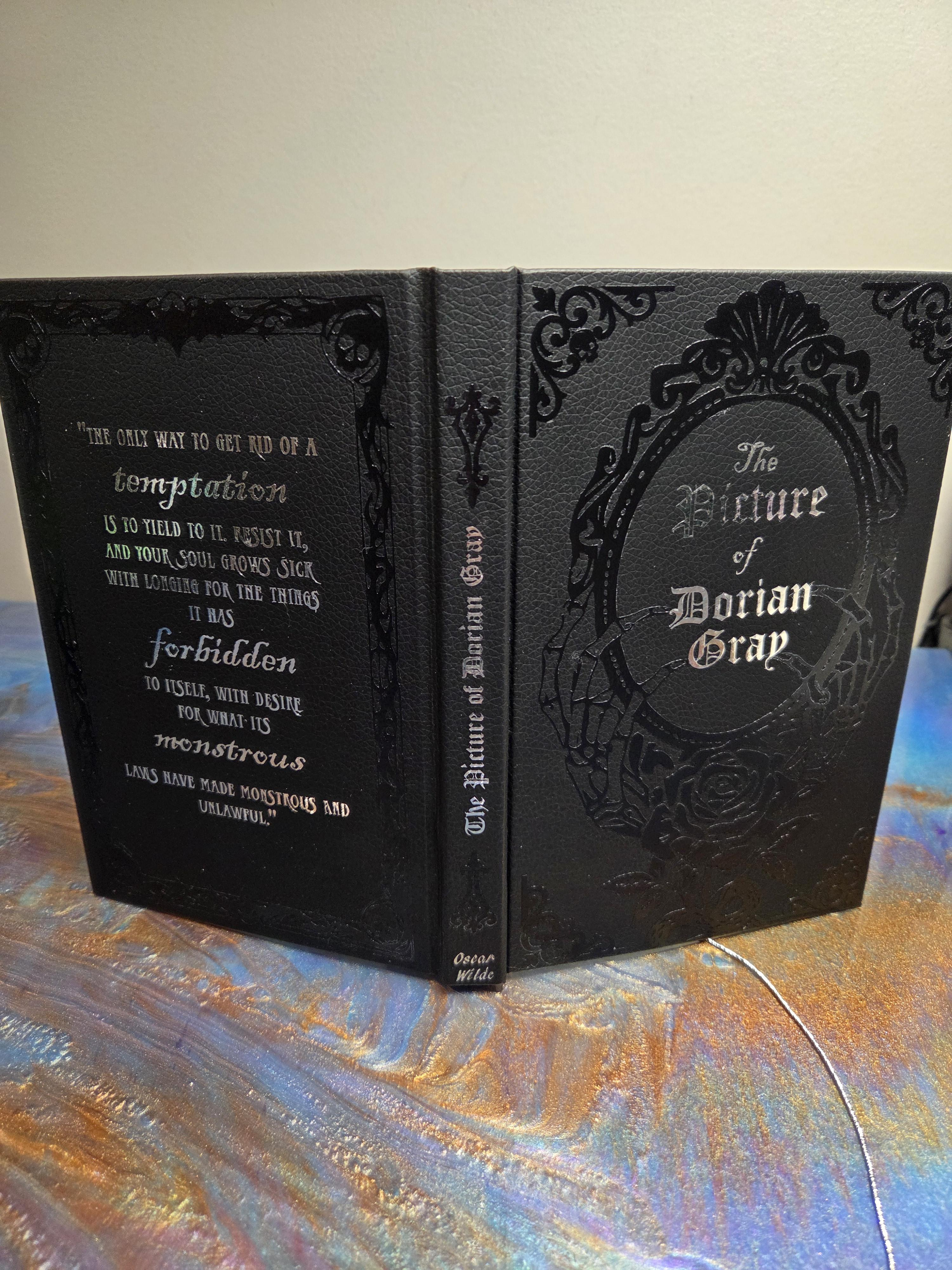 black faux leather embossed with black and silver details. the cover and spine has the title. the back has a beautifully typeset in silver key quote from the book.
