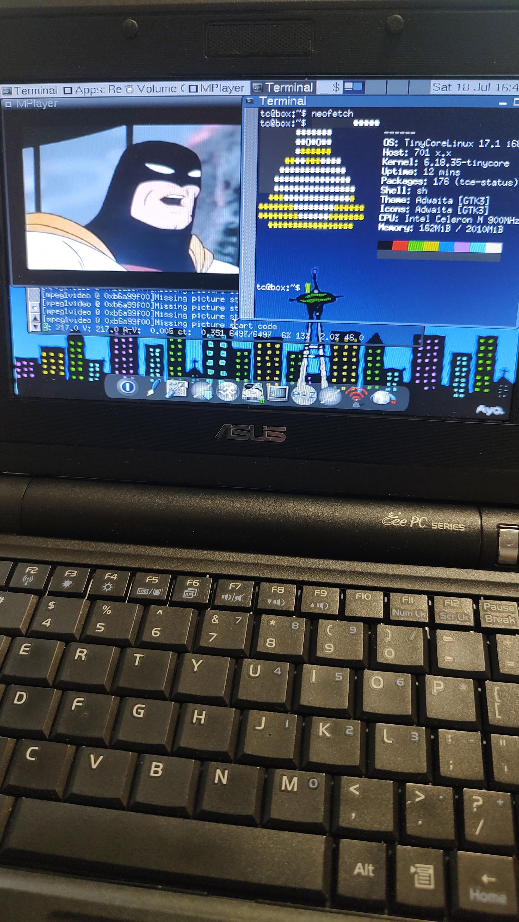 An Asus Eee PC 701 netbook, running Tiny Core Linux (as seen on a terminal showing a neofetch output), and Space Ghost is here too