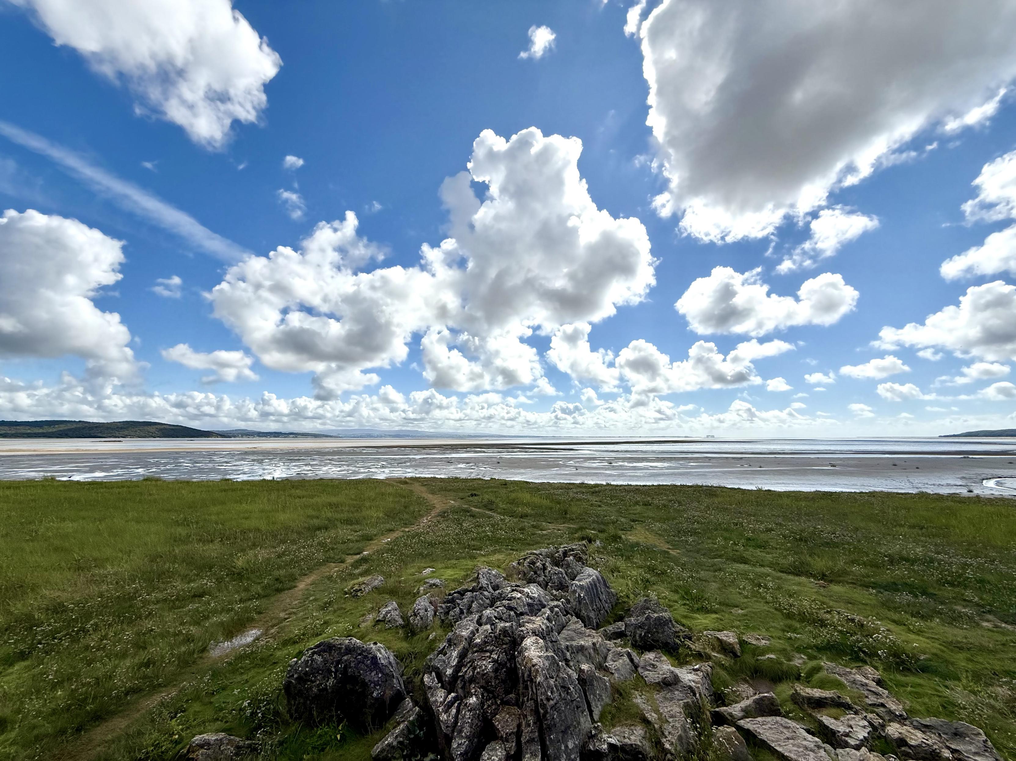 View across a bay under blue sky with white fluffy clouds