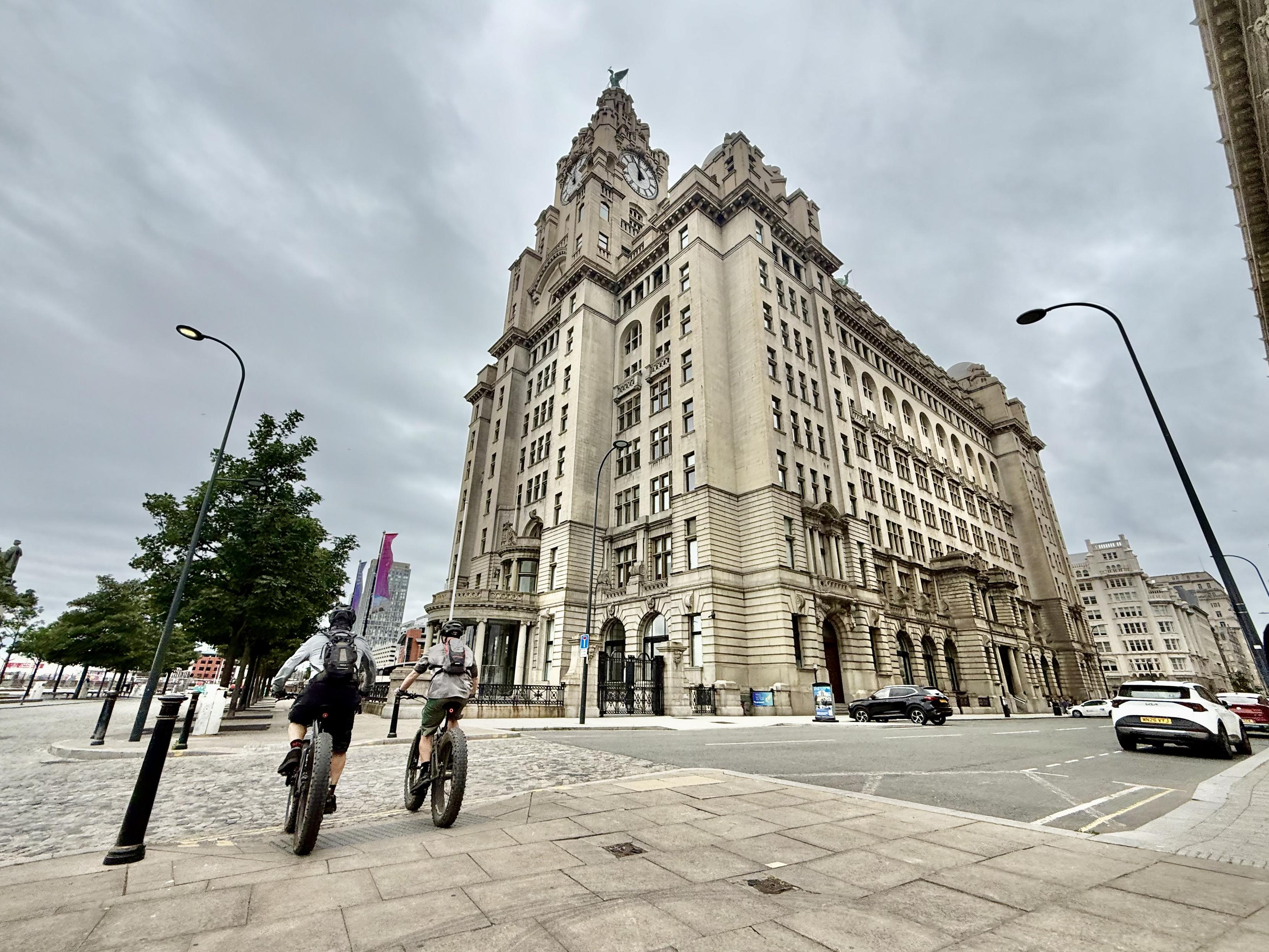 Two cyclists passing the Liver Building