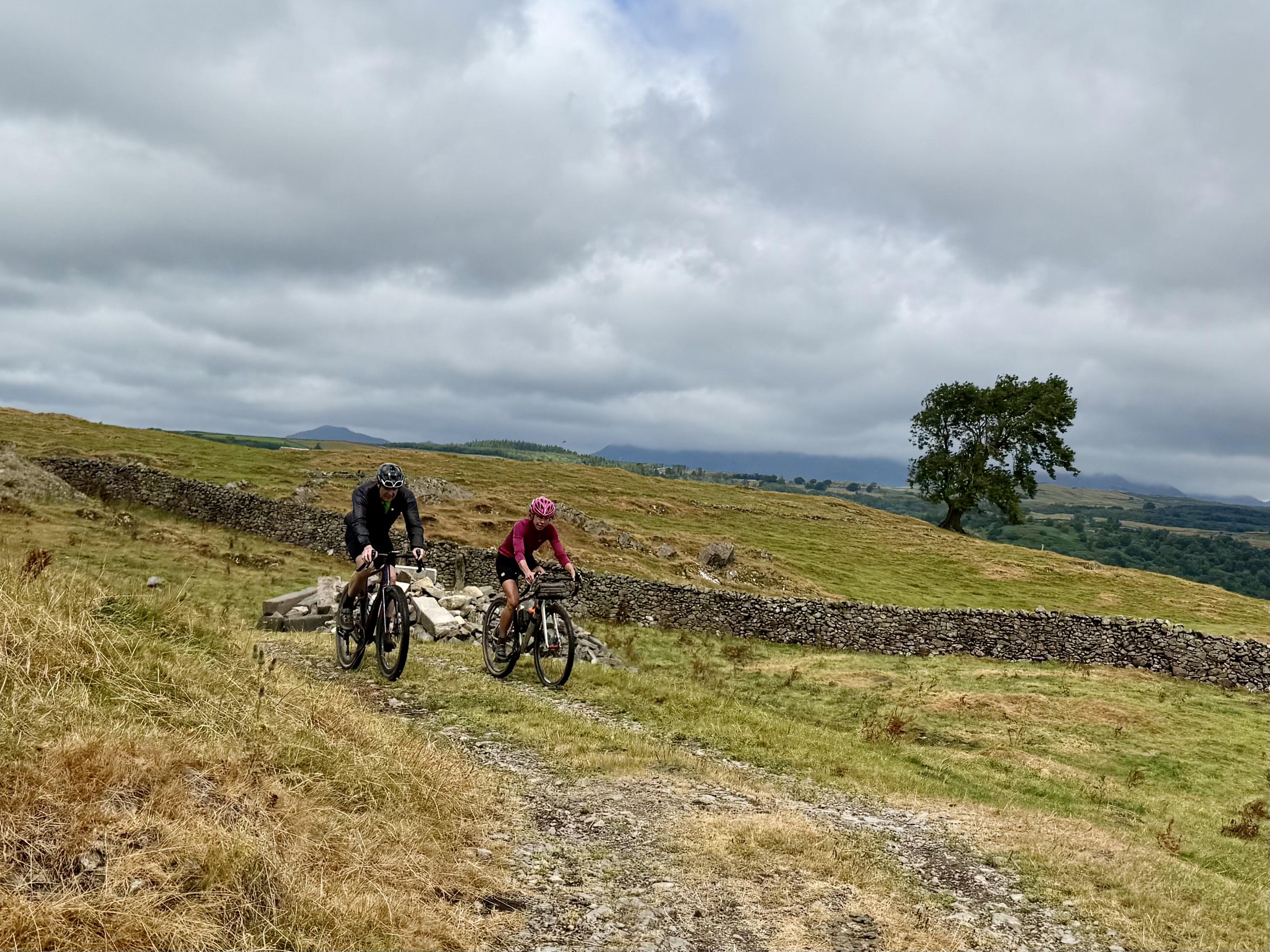 Cyclists heading left to right along a gravel track