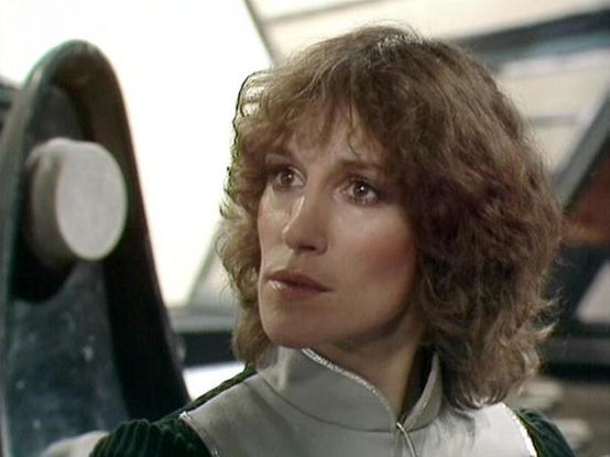 ChatGPT4 describes the image as: "The image depicts a person with curly hair, wearing a high-collared outfit that appears to be part of a science fiction setting. The background suggests a futuristic or spaceship-like environment with metallic and geometric shapes. The lighting and design give it a classic sci-fi vibe from the late 1970s or early 1980s."

Blakes7Bot, version 3.7.34.