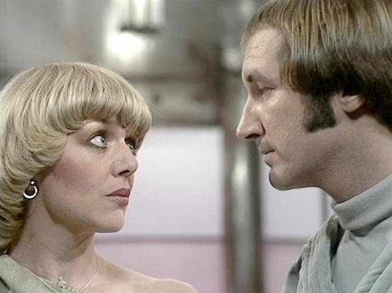 Claude Sonnet 4.0 describes the image as: "I can see two people in what appears to be a science fiction setting, likely aboard a spacecraft or futuristic facility. The woman has a distinctive blonde feathered hairstyle typical of 1970s television, and is wearing what looks like a light-colored outfit with earrings. The man has shoulder-length hair and is wearing what appears to be a high-collared jacket or uniform in muted tones. They appear to be having an intimate or serious conversation, fac…