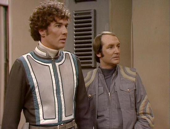 Claude Sonnet 4.0 describes the image as: "This scene shows two characters in what appears to be an interior setting, likely aboard a spacecraft or space station based on the utilitarian wall panels and ventilation visible in the background. The man on the left wears a distinctive white and gray uniform with geometric trim and piping, featuring a high collar - typical of the series' futuristic costume design. The man on the right is dressed in a more casual gray jumpsuit or work outfit. Both ap…