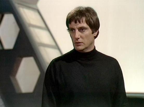 Claude Sonnet 4.0 describes the image as: "This image shows a scene with dramatic lighting and shadows cast across a futuristic interior setting. The character is wearing a dark, high-collared outfit typical of the series' distinctive costume design. The background features the show's characteristic sterile, technological aesthetic with clean lines and geometric patterns. The lighting creates an atmospheric effect with strong contrasts between light and shadow, emphasizing the serious, tense mo…