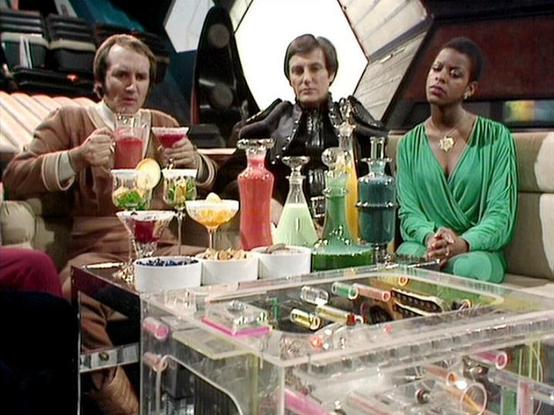 Claude Sonnet 4.0 describes the image as: "I can see three people seated around a clear/transparent table with various colorful drinks and cocktails. The setting appears to be a futuristic lounge or recreational area with sleek, modern furnishings and what looks like a spaceship interior in the background. The person on the left is wearing earth-toned clothing and appears to be drinking, the middle figure is dressed in dark leather or similar material, and the person on the right is wearing a s…