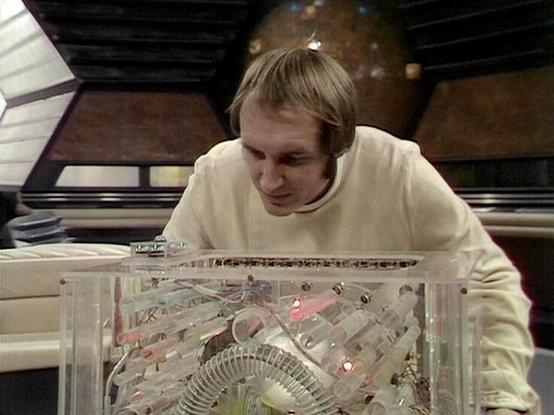 Claude Sonnet 4.0 describes the image as: "I can see this is a scene showing someone in white clothing examining what appears to be a complex technological device or control panel with a transparent casing. The device contains intricate circuitry, wiring, and small lights, suggesting it's some kind of advanced computer or navigation system. The setting appears to be inside a spaceship or advanced facility, with sleek metallic surfaces and futuristic architecture visible in the background. The p…