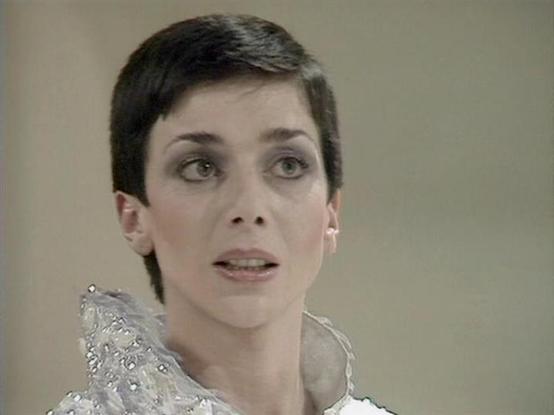 Claude Sonnet 4.0 describes the image as: "I can see this is a scene from a science fiction television series featuring a character with very short, dark hair wearing what appears to be an ornate, light-colored costume with decorative elements around the collar or shoulder area. The setting appears to be an interior space with neutral-toned walls. The character appears to be in the middle of delivering dialogue, with an intense or serious expression. The production values and visual style sugge…