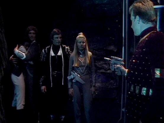 Claude Sonnet 4.0 describes the image as: "This appears to be a scene set aboard a spacecraft, likely the Liberator or Scorpio, with the characteristic dark, high-tech interior typical of the series. The lighting creates a moody atmosphere with the crew gathered in what looks like the main control area or flight deck. The setting suggests this is during a tense moment or important discussion, with the characters positioned around the ship's central console area. The production design shows the …