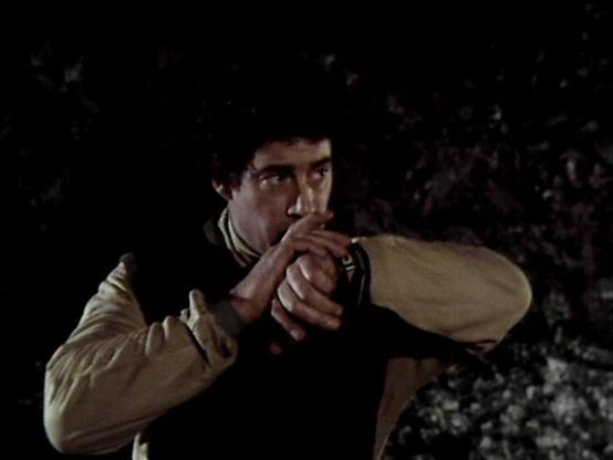 Claude 3.7 describes the image as: "This image appears to be from a vintage science fiction television production, likely from the late 1970s or early 1980s based on the film quality and aesthetic. The scene shows a person in a two-tone jacket (dark vest/body with lighter colored sleeves) in what seems to be a dimly lit, possibly cave-like or outdoor nighttime setting.

The individual appears to be in a tense moment, possibly holding or aiming something, suggesting this might be from an action …