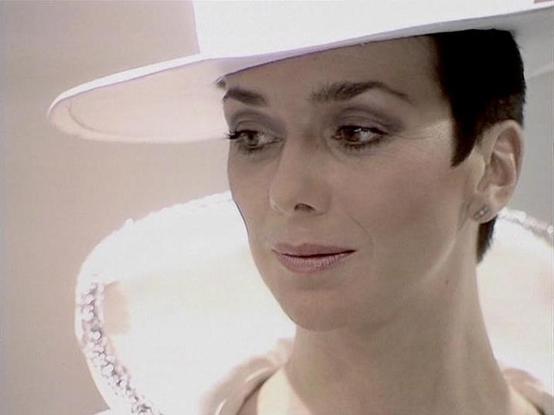 Claude Sonnet 4.0 describes the image as: "I can see this is a science fiction production featuring a person in futuristic white costume and headwear. The image shows someone wearing what appears to be an elaborate white outfit with decorative elements and a distinctive white hat or headpiece. The setting appears to be a futuristic or sci-fi environment with clean, white/light colored surfaces. The costume design and production values suggest this is from a television series, likely from the la…