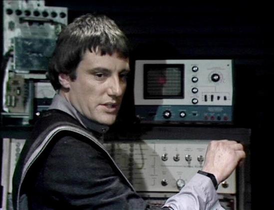 Claude Sonnet 4.0 describes the image as: "This image shows a scene set in what appears to be a spacecraft's control room or technical facility, filled with futuristic computer equipment and monitoring devices typical of 1970s science fiction television. The setting features various control panels, screens, and electronic instruments that create an authentic spaceship bridge atmosphere. The person in the image is wearing what appears to be a dark uniform or outfit consistent with the show's dis…