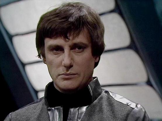 Claude Sonnet 4.0 describes the image as: "This image shows a character in what appears to be a futuristic military or space-faring uniform, featuring a distinctive silver/metallic outfit with a high collar. The setting has a science fiction aesthetic with geometric lighting patterns visible in the background, creating an atmospheric, spaceship-like environment. The lighting creates dramatic shadows and highlights that emphasize the serious, contemplative expression of the figure. The costume d…