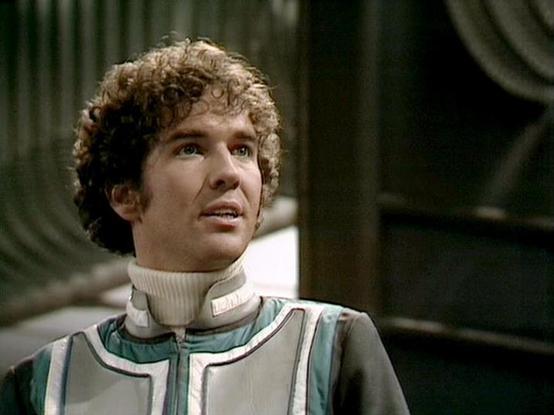 Claude Sonnet 4.0 describes the image as: "I can see this is a scene featuring a character in a distinctive white and teal colored futuristic uniform with high collar details, characteristic of the show's sleek costume design. The setting appears to be aboard a spacecraft, with the typical metallic interior and curved architectural elements visible in the background. The lighting creates the moody, dramatic atmosphere the series was known for. The uniform's design reflects the show's aesthetic …
