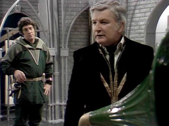 Claude Sonnet 4.0 describes the image as: "This scene shows two characters in what appears to be a futuristic or space-age setting with distinctive architectural elements featuring arched doorways and metallic surfaces. One figure is wearing a dark formal outfit with ornate gold braiding or decorative elements, suggesting a position of authority or high rank. In the background, another character can be seen wearing a green hooded garment. The setting has a institutional or governmental appearan…