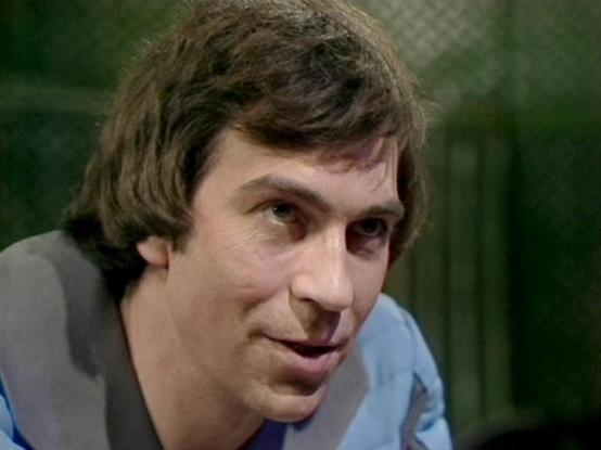 Claude 3.7 describes the image as: "The image appears to be a still from a television production from what looks like the late 1970s or early 1980s, based on the visual quality and style. It shows a person with medium-length brown hair in what appears to be an indoor setting with a greenish background. They're wearing what looks like casual attire with blue and gray elements visible. The lighting and film quality have that distinctive vintage television production look characteristic of British…