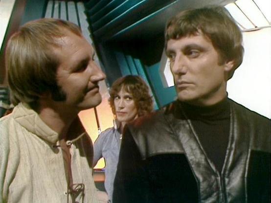 Claude Sonnet 4.0 describes the image as: "This scene appears to be set aboard the Liberator spacecraft, with its distinctive curved walls and technological interior visible in the background. The setting has the characteristic futuristic design of the ship's corridors or flight deck area. Three crew members are present in what appears to be a tense moment - two men are positioned close together in what seems to be a confrontational or intense discussion, while a third person with curly hair ob…