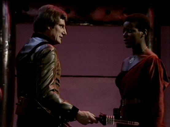 Claude Sonnet 4.0 describes the image as: "In this scene, two characters are engaged in what appears to be a tense conversation aboard a spacecraft. The setting has the distinctive purple-tinted lighting and metallic interior design typical of the series. One character wears a dark leather outfit with metallic studs or details, while the other is dressed in flowing red and dark clothing. They appear to be standing close together in what looks like a corridor or chamber of the ship, suggesting a…