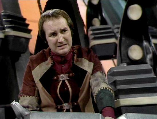 Claude Sonnet 4.0 describes the image as: "I can see this appears to be from a science fiction television production, showing someone in elaborate period-style costume with rich fabrics in burgundy and earth tones, featuring ornate fastenings and detailed sleeves. The setting appears to be a futuristic or spaceship-like environment with metallic surfaces and circular design elements visible in the background. The costume design suggests this might be from a formal or ceremonial scene, with the …