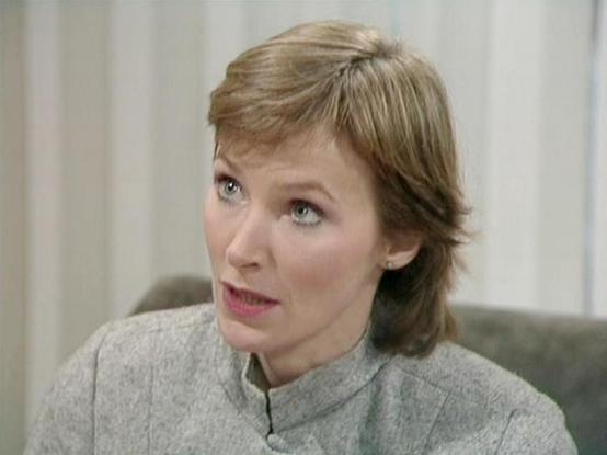 Claude 3.7 describes the image as: "This image shows a scene from what appears to be a vintage television production, likely from the late 1970s or early 1980s based on the visual style and production quality. 

The person in the image has short, light brown hair and is wearing a gray high-collared outfit, which fits with the futuristic or sci-fi aesthetic common in productions of that era. Their expression appears concerned or intense, suggesting this might be from a dramatic scene.

The backg…