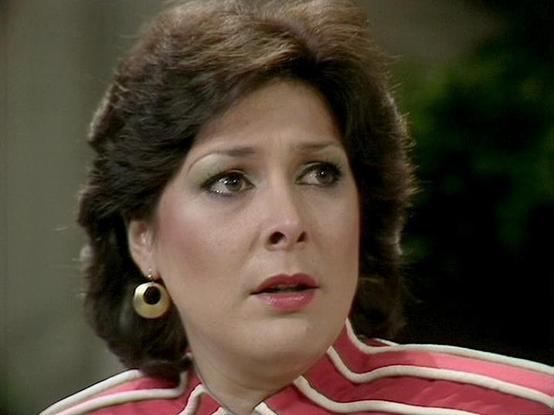 Claude Sonnet 4.0 describes the image as: "I can see this is an image from a television production showing someone in what appears to be a dramatic scene. The person is wearing a striped red and white top and circular earrings, with styled hair typical of 1970s-80s television production. The lighting and image quality suggest this is from a science fiction series of that era. The setting appears to be indoors with soft lighting in the background. However, I cannot identify who the specific acto…