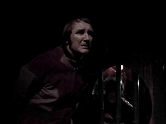 Claude 3.7 describes the image as: "This image appears to be from a dark, dramatic scene, likely filmed in a low-light setting. The photo shows a person wearing what looks like a utilitarian or military-style jacket in a brownish color. They appear to be in some kind of dimly lit environment, possibly a corridor or confined space.

The dramatic lighting creates strong shadows and a tense atmosphere, which was characteristic of the sci-fi television production styles of the late 1970s/early 1980…