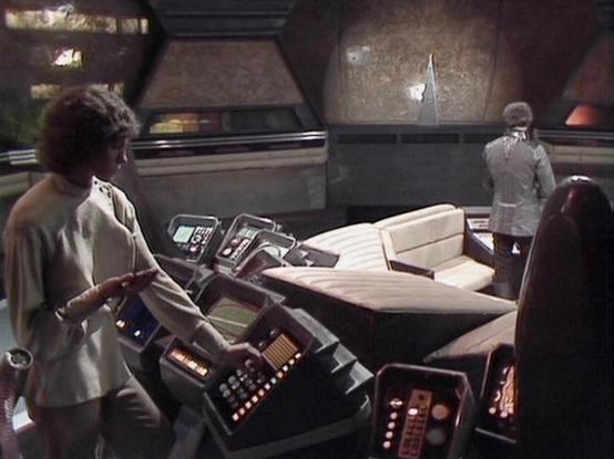 Claude Sonnet 4.0 describes the image as: "I can see this appears to be from a science fiction television series, showing the interior of what looks like a spacecraft or control room. The setting features futuristic control panels with various buttons, switches, and displays typical of 1970s-80s sci-fi production design. There are comfortable-looking seats and the overall aesthetic has that distinctive retro-futuristic appearance common to British science fiction shows of that era. The lighting…