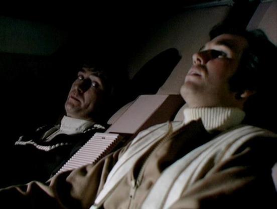 Claude Sonnet 4.0 describes the image as: "I can see this appears to be from a science fiction television production, showing two people in what looks like a spacecraft or futuristic vehicle interior. The lighting is dramatic and moody, with both figures wearing light-colored clothing. The setting has the characteristic look of 1970s/80s sci-fi television production design, with angular surfaces and technical equipment visible in the background. The scene appears tense or dramatic based on the …