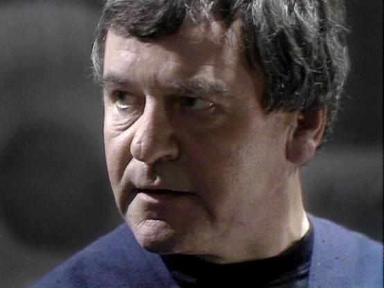 Claude 3.7 describes the image as: "I can see a close-up portrait of a middle-aged man wearing a blue uniform with a black undershirt, which appears to be from a science fiction television production. The image shows professional lighting and appears to be from a television broadcast or film production, likely from the 1960s or 1970s based on the video quality and color grading.

The setting appears to be an indoor studio environment with a blurred background, typical of television production f…