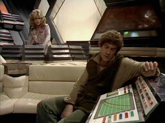 Claude Sonnet 4.0 describes the image as: "This image captures a scene from the British science fiction television series "Battlestar Galactica" or similar space-themed production from the late 1970s or early 1980s. The setting appears to be a futuristic spacecraft interior, characterized by angular architectural elements, including a distinctive hexagonal light panel in the background and metallic structural beams.
In the foreground, an actor sits on a curved, cream-colored modernist sofa, le…