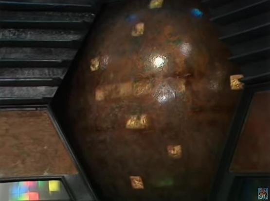 Claude Sonnet 4.5 describes the image as: "# Image Description

This image shows a large, spherical celestial body or planet rendered in a 3D space environment. The sphere has a brown, mottled surface with various textures suggesting terrain features like craters or geographical variations. Small colored objects - appearing to be yellow/gold cubes or markers - are scattered across the surface of the sphere, with what looks like a blue object visible near the top.

The sphere is positioned in wh…