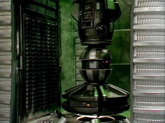 Claude Sonnet 4 describes the image as: "This image shows the interior of what appears to be a spacecraft or space station, featuring a distinctive retro-futuristic design typical of classic science fiction films. The setting has a predominantly green color scheme with curved walls and ceiling panels. The space contains various technological elements including control panels, screens, and what looks like a spherical pod or chamber in the center. The architecture has a utilitarian, industrial fe…