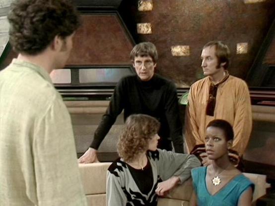 Claude Sonnet 3.7 describes the image as: "This image appears to be from the British science fiction television series "Blake's 7." The scene shows a group of characters on what looks like a spaceship set with distinctive 1970s/80s sci-fi aesthetic, featuring textured walls and futuristic design elements.

The image captures five people in a tense discussion or confrontation. They're dressed in characteristic science fiction attire of the era - simple but distinctive costumes in various colors …