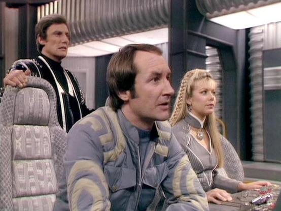 Claude Sonnet 4 describes the image as: "This appears to be a scene from the British science fiction television series "Blake's 7." The image shows three characters in what looks like the interior of a spaceship or futuristic setting, with metallic corridors and modern lighting visible in the background. The characters are wearing distinctive costumes typical of late 1970s/early 1980s sci-fi productions - including leather-like outfits and futuristic styling. The setting appears to be aboard th…