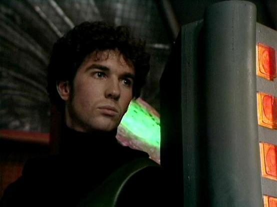 Claude Haiku 4.5 20251001 describes the image as: "# Image Description

This image shows a person in a dimly lit, industrial setting that appears to be inside some kind of facility or vessel. The scene has a distinctly cinematic quality with moody lighting. The individual is positioned in profile, looking pensively to the side, wearing dark clothing that blends with the shadowy environment.

The setting features metallic elements, including what appears to be a large cylindrical pipe or structu…