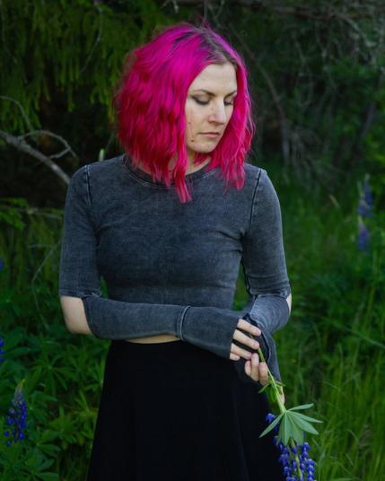 A pink haired woman surrounded by lupines